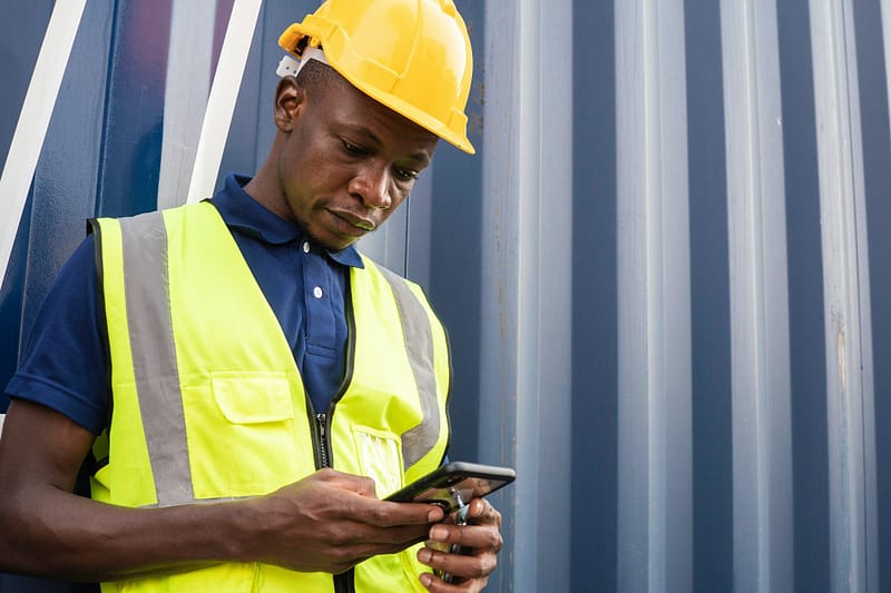 African American worker checking information on phone at construction site